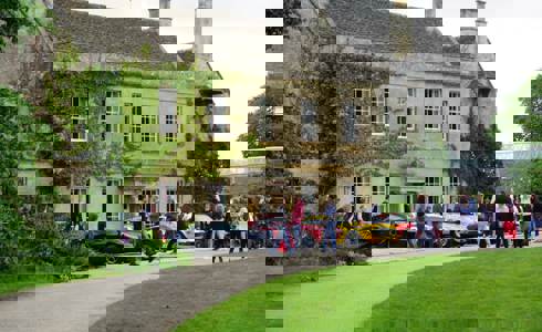 A photo of Middlewick House with sports cars parked outside and visitors taking photos and looking at the cars.