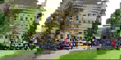 A photo of Middlewick House with sports cars parked outside and visitors taking photos and looking at the cars. A photo of Middlewick House with sports cars parked outside and visitors taking photos and looking at the cars.