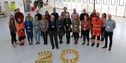 A photo of charity team members with yellow collection tins arranged in the number 20.