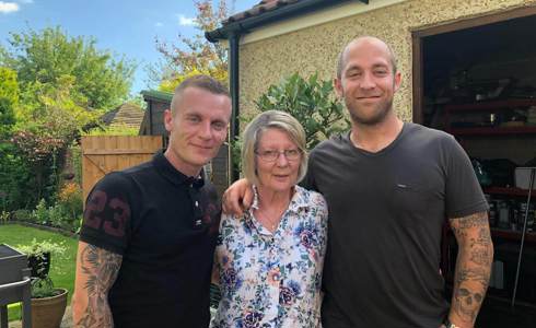 A former patient with their two children stood in a garden