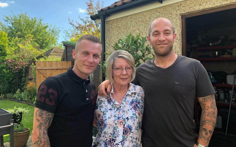 A former patient with their two children stood in a garden