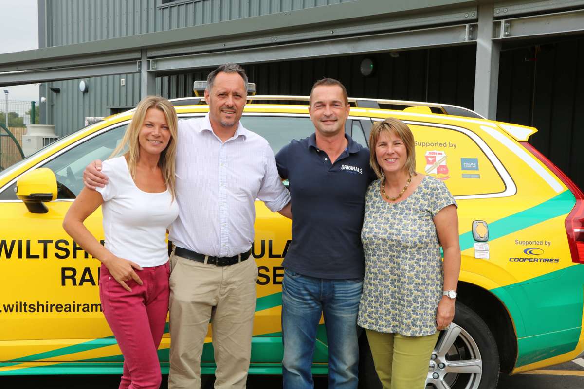 A former patient and their partner visiting Wiltshire Air Ambulance, the group are with a paramedic and pilot stood in front of the critical care car.