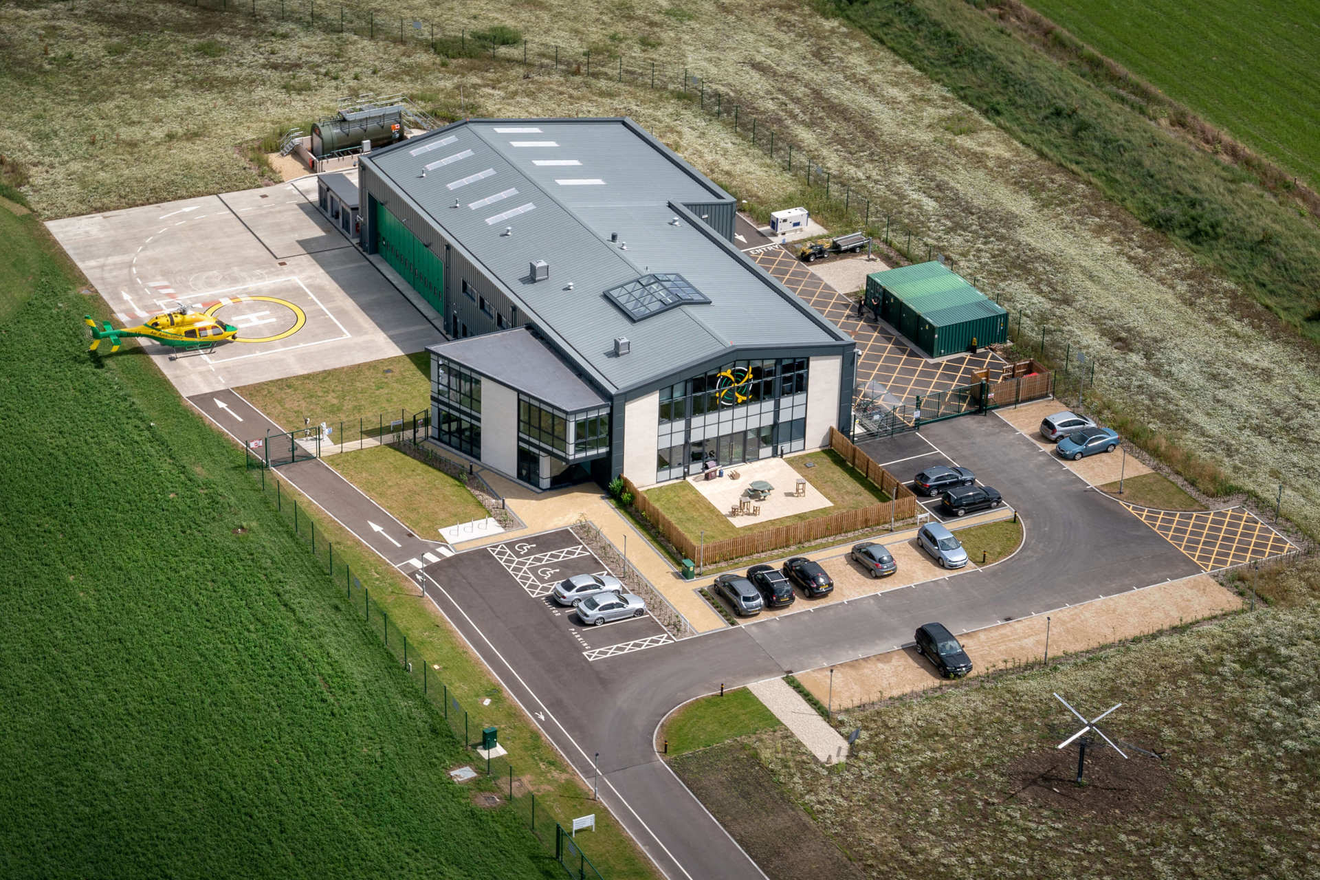 An aerial photo of the Wiltshire Air Ambulance airbase with the helicopter landing on its helipad.