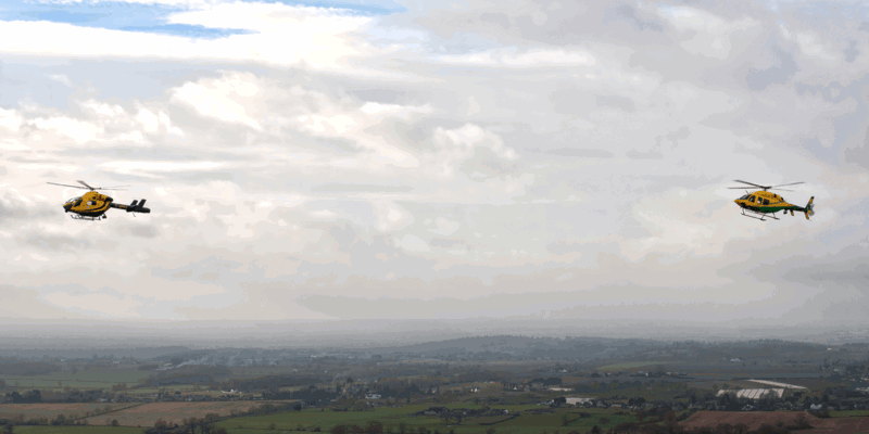 The old Wiltshire Air Ambulance MD-902 helicopter in the air, flying alongside the new Bell-429 helicopter.