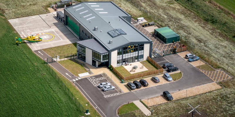 An aerial photo of the Wiltshire Air Ambulance airbase featuring the Bell-429 helicopter landing on its helipad.