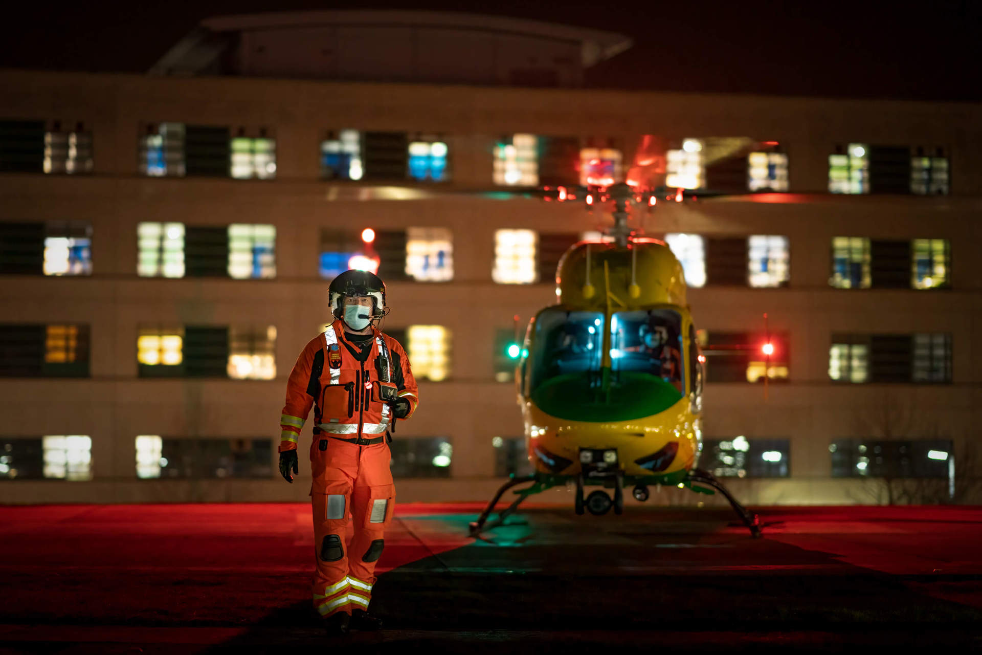 A critical care paramedic stood in front of the helicopter which has landed on the helipad at Great Western Hospital at night.