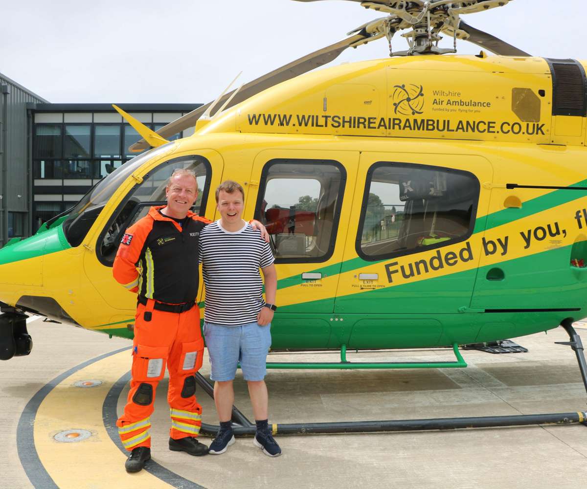 A former patient meeting critical care paramedic at the charity's airbase. They are stood in front of the helicopter on the helipad.