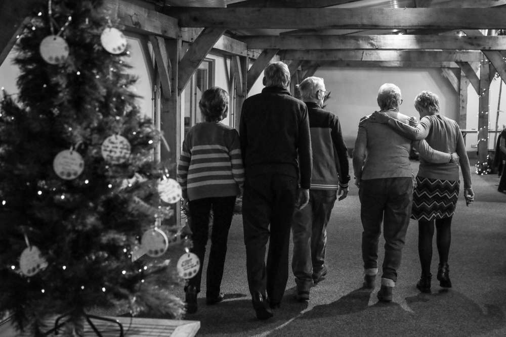 Black and white photo of family comforting each other with their backs to camera.