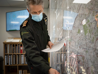 Pilot Elvis wearing a face mask and planning a route on a map in the Wiltshire Air Ambulance ops room Pilot Elvis wearing a face mask and planning a route on a map in the Wiltshire Air Ambulance ops room