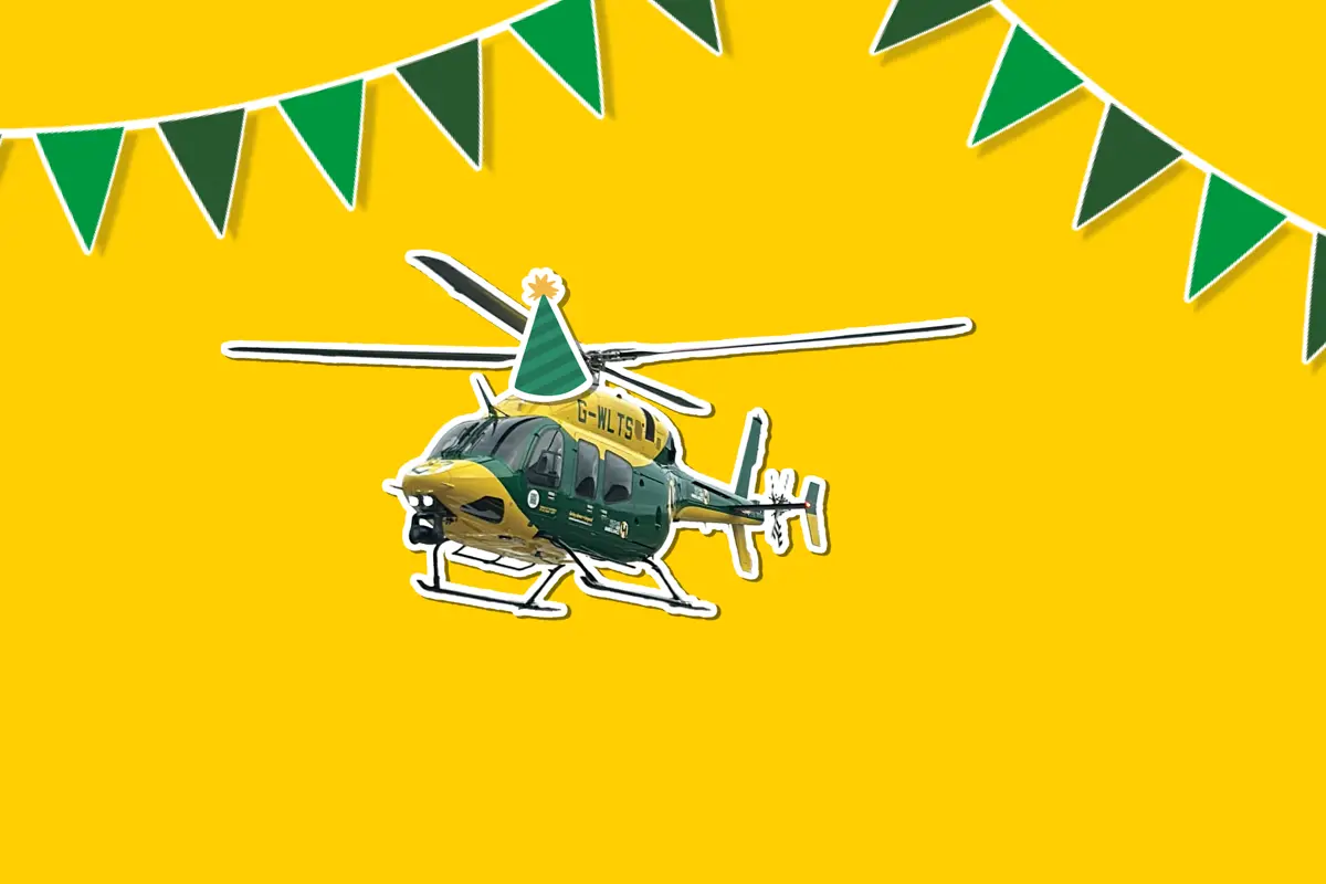 A yellow background with a sticker of the yellow and grey Bell 429 helicopter wearing a cartoon sticker hat, with green bunting around it