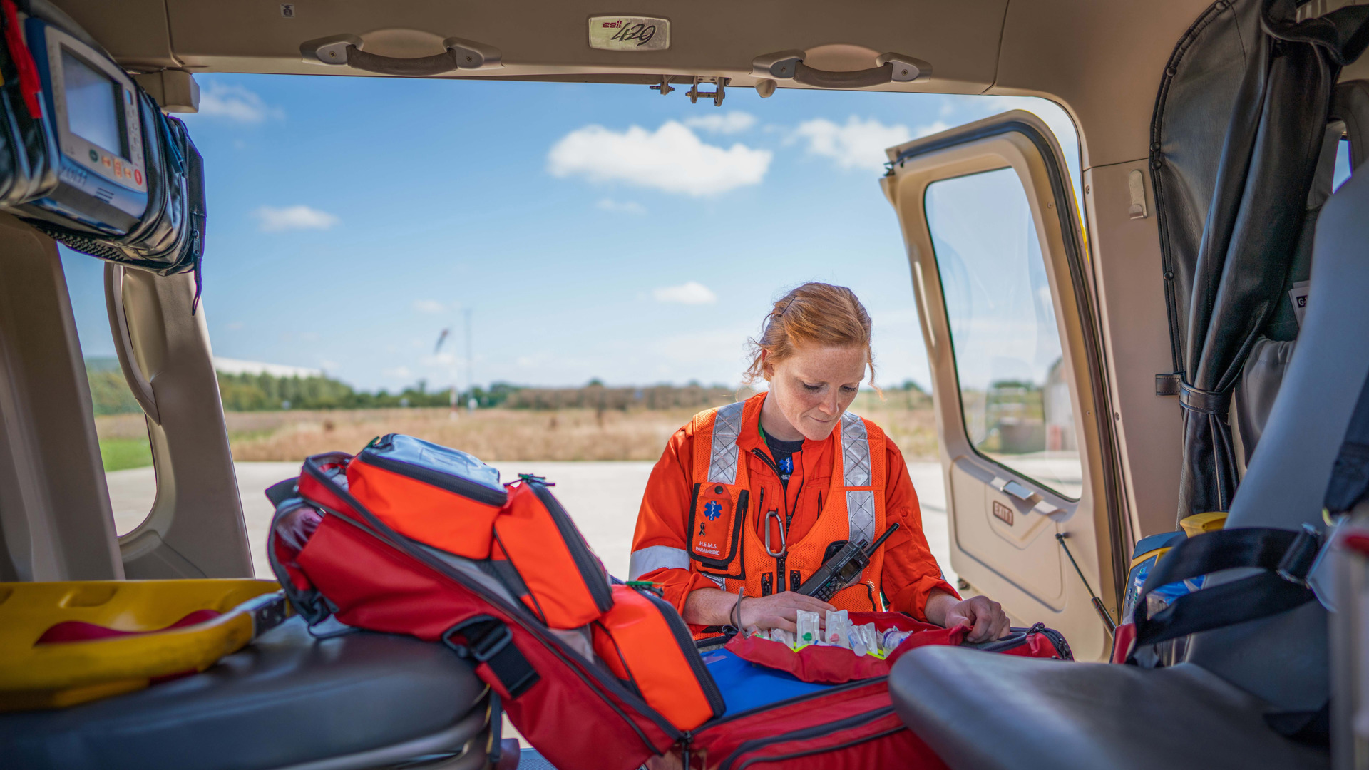 A paramedic looking in a kit bag, which is inside a helicopter