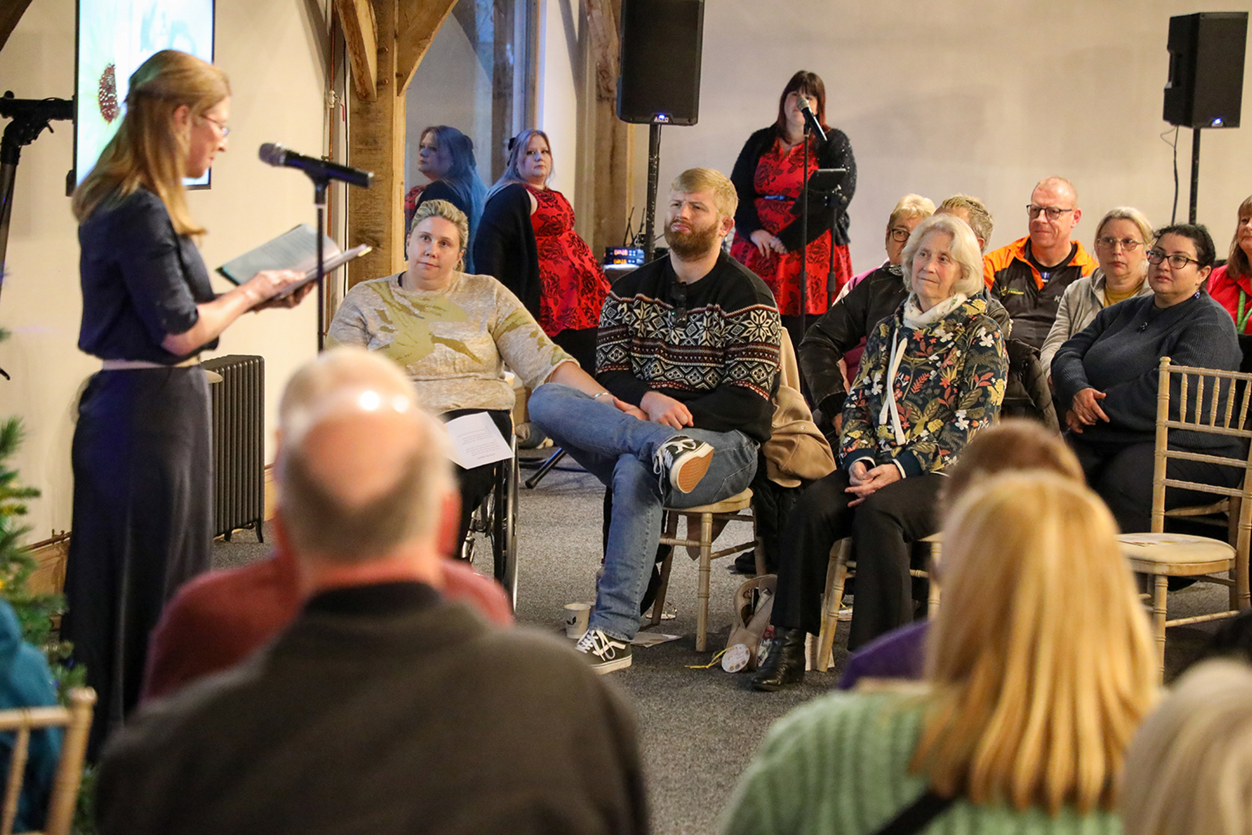 A celebrant speaking in to a microphone to a group of seated people