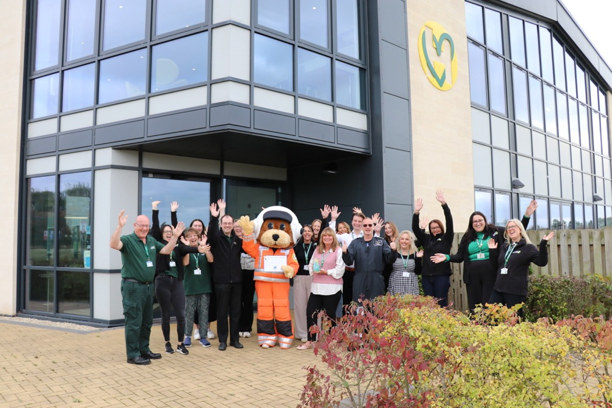 The charity team and mascot celebrating outside the airbase holding a vase award and certificate