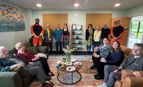 A group of people, some sitting on sofas, unveiling a new comfortable room