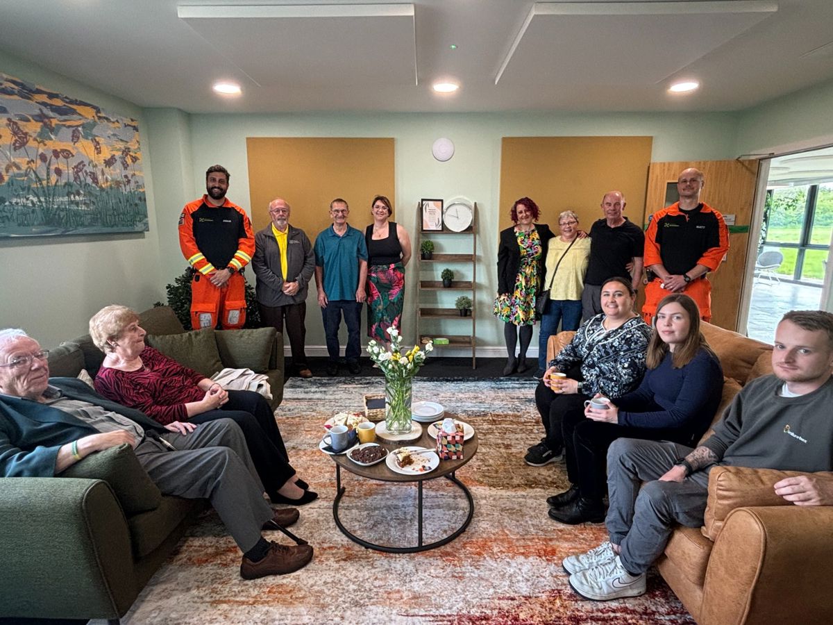 A group of people, some sitting on sofas, unveiling a new comfortable room