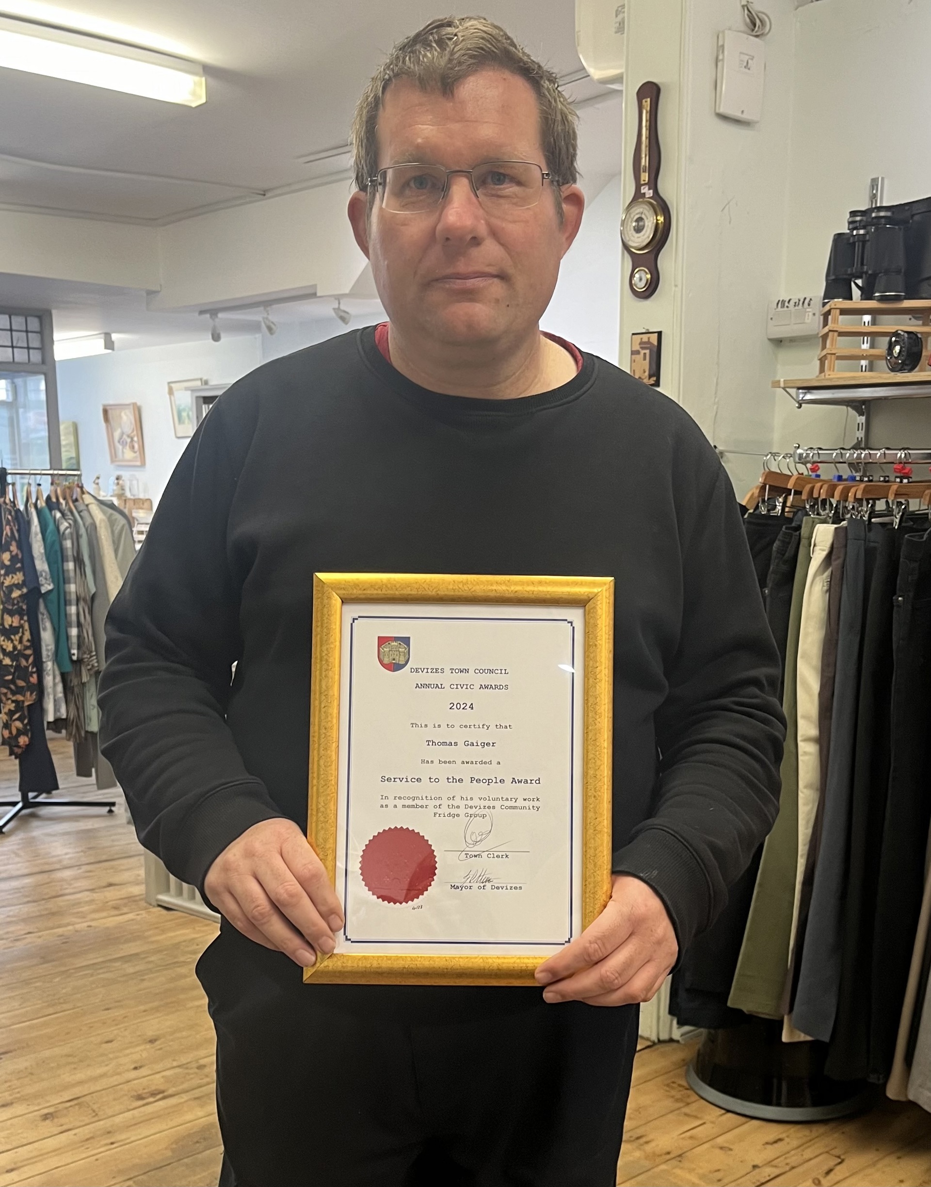 A volunteer holding an award in gold frame