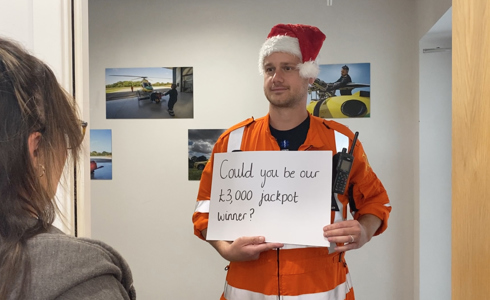 A paramedic wearing a santa hat, holding a "could you be out £3,000 jackpot winner" sign, like in Love Actually