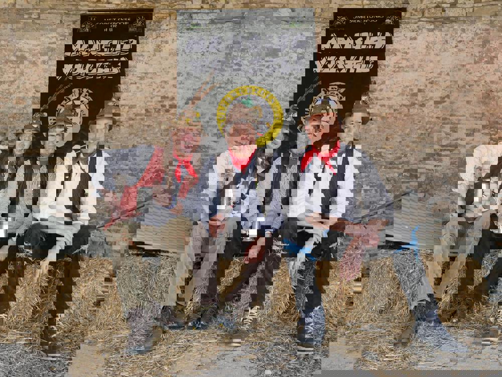 A photo of The Mangled Wurzels sitting on bales of hay