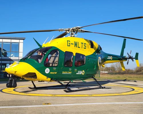 Yellow and green helicopter on helipad with blue sky behind