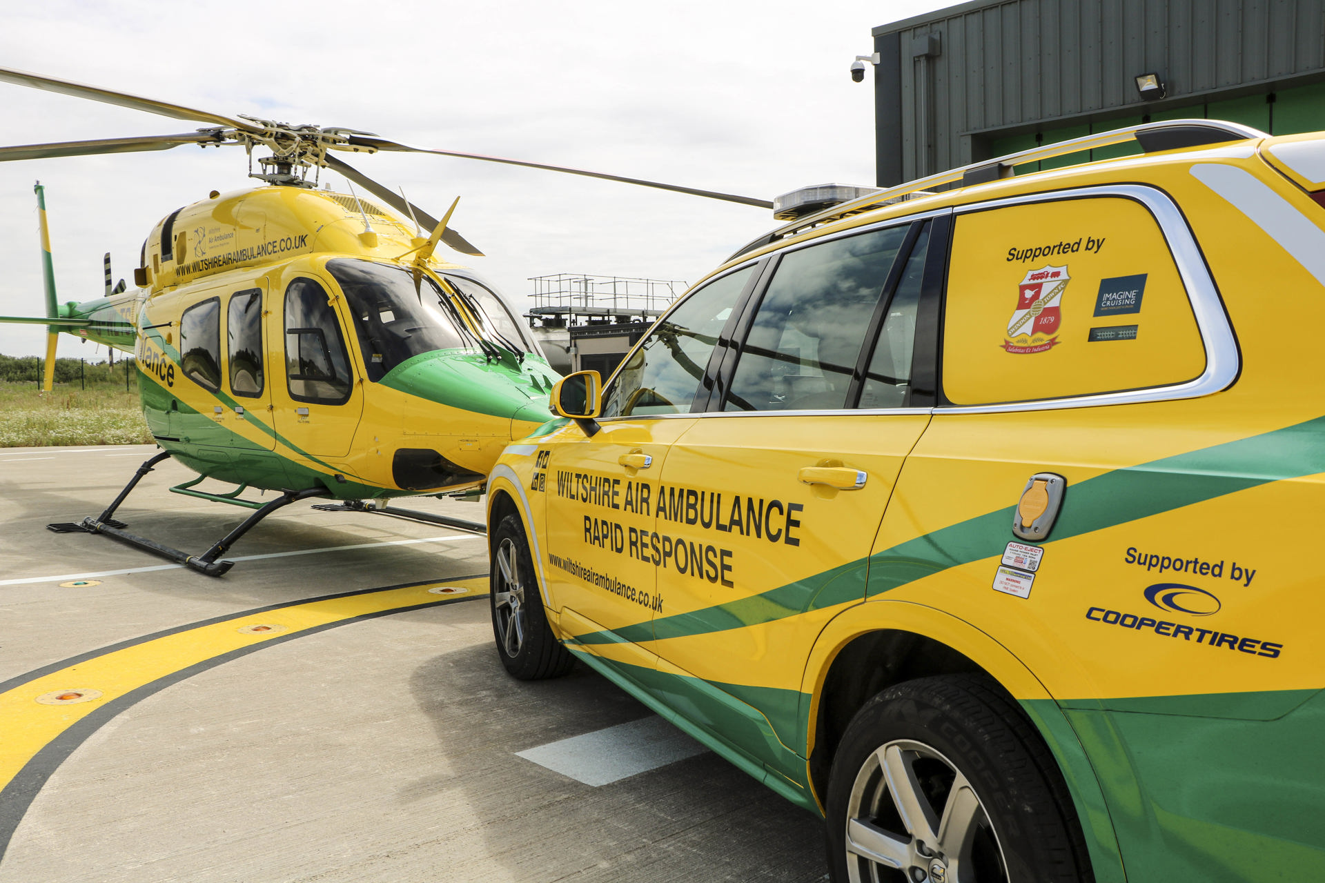 The Wiltshire Air Ambulance helicopter and critical care car on the helipad at the airbase.