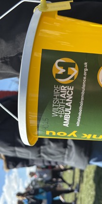 A yellow collection bucket with green label showing W+BAA logo and donation information