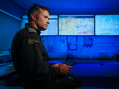 Pilot Matt looking at screens in Wiltshire Air Ambulance's ops room with ipad in hand