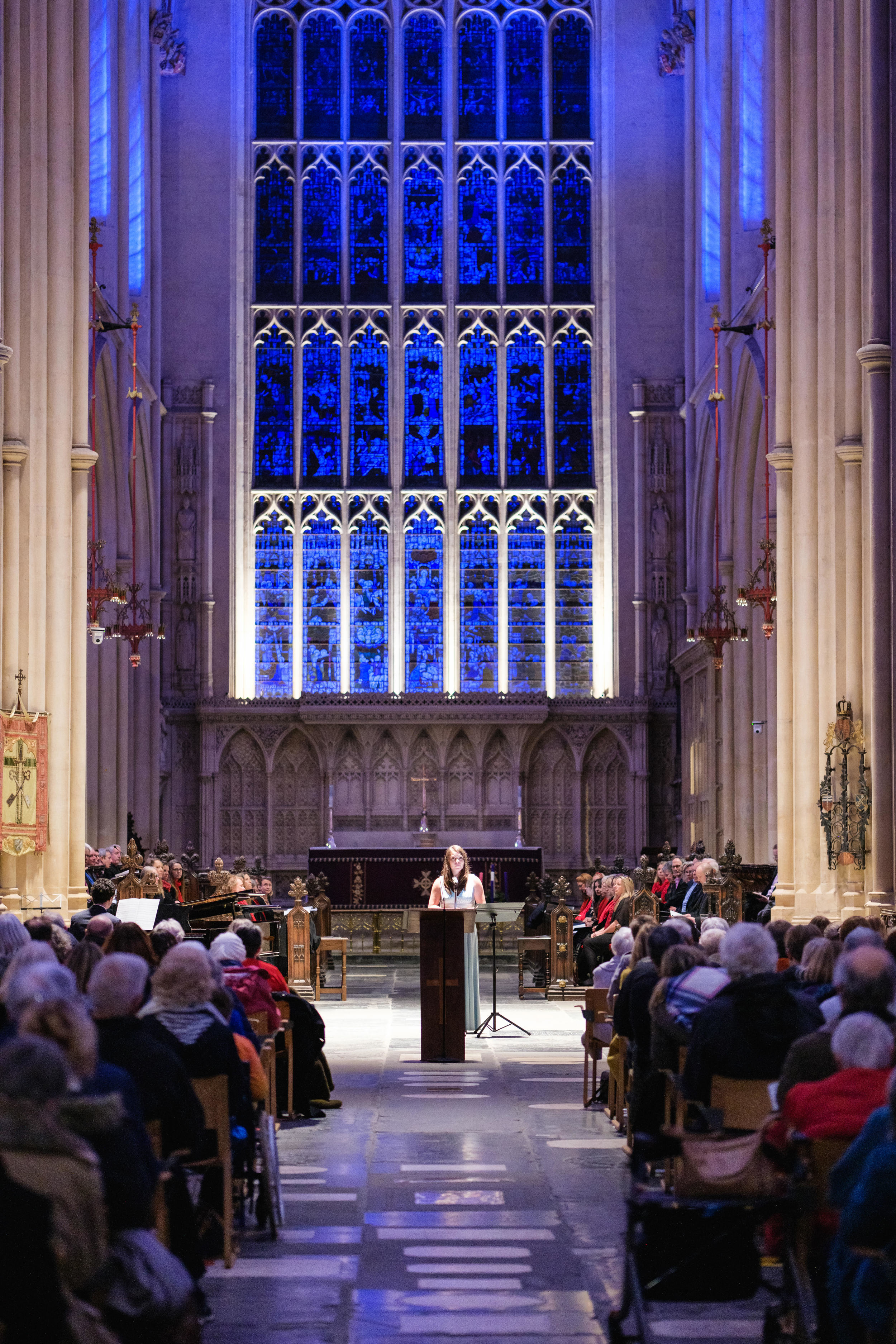 A singer singing at the front of Bath Abbey to a crowd of people